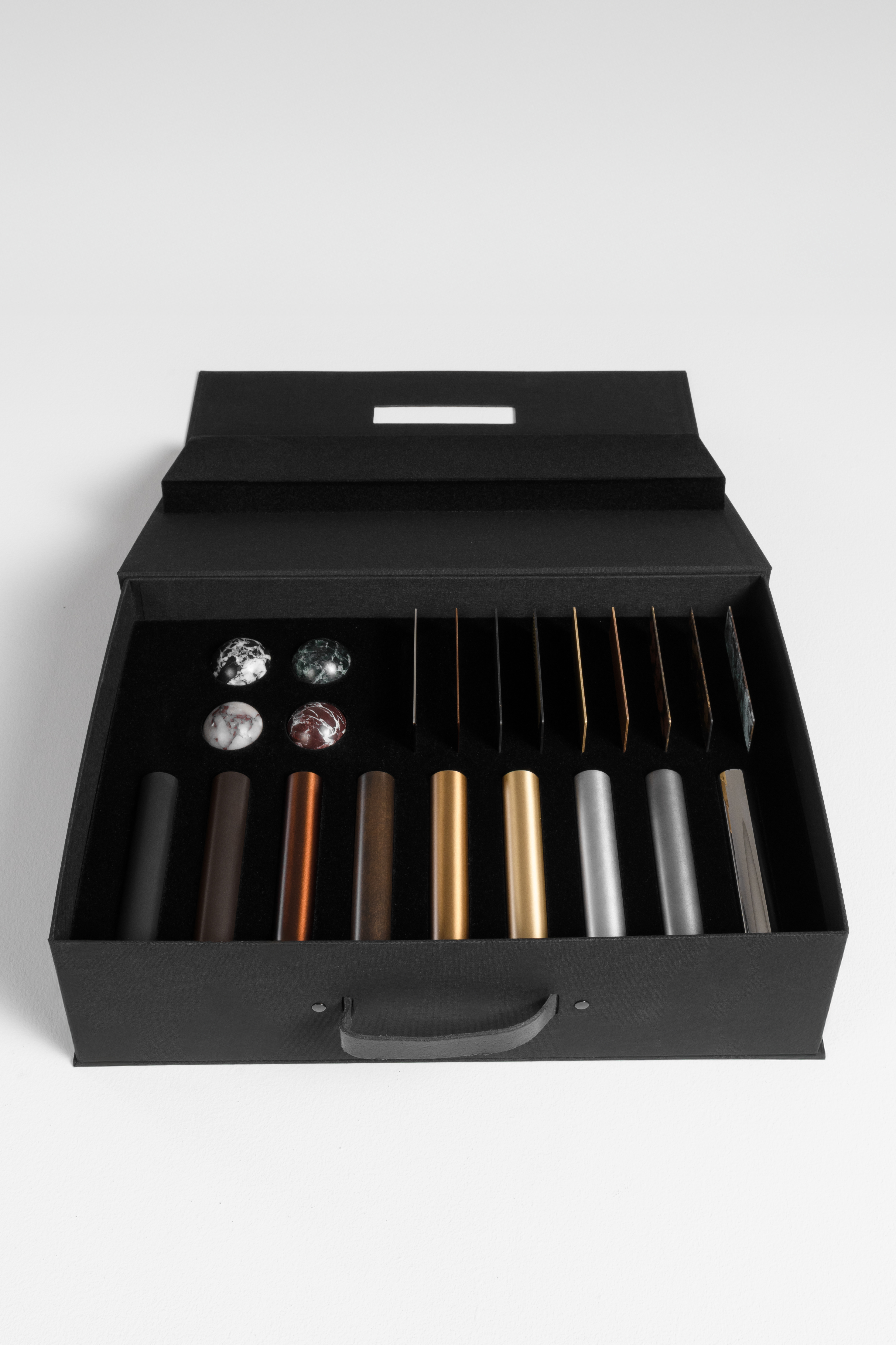 Schwung Finish Sample Box featuring marble spheres, brass finish tubes and 10 × 10 cm finish plates for handcrafted lighting projects.