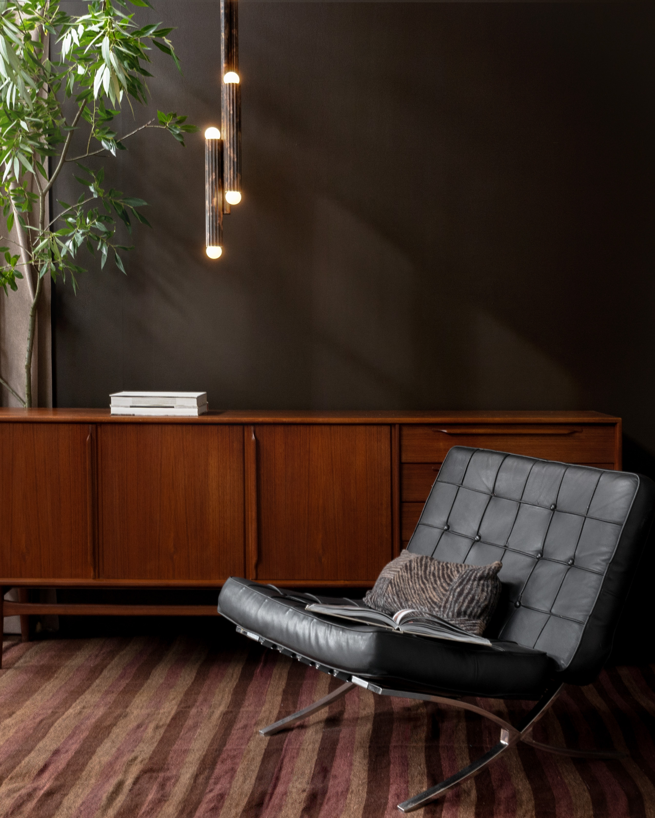 Vesta pendant in rose ash finish, suspended above a refined interior with wooden sideboard and leather lounge chair by Schwung