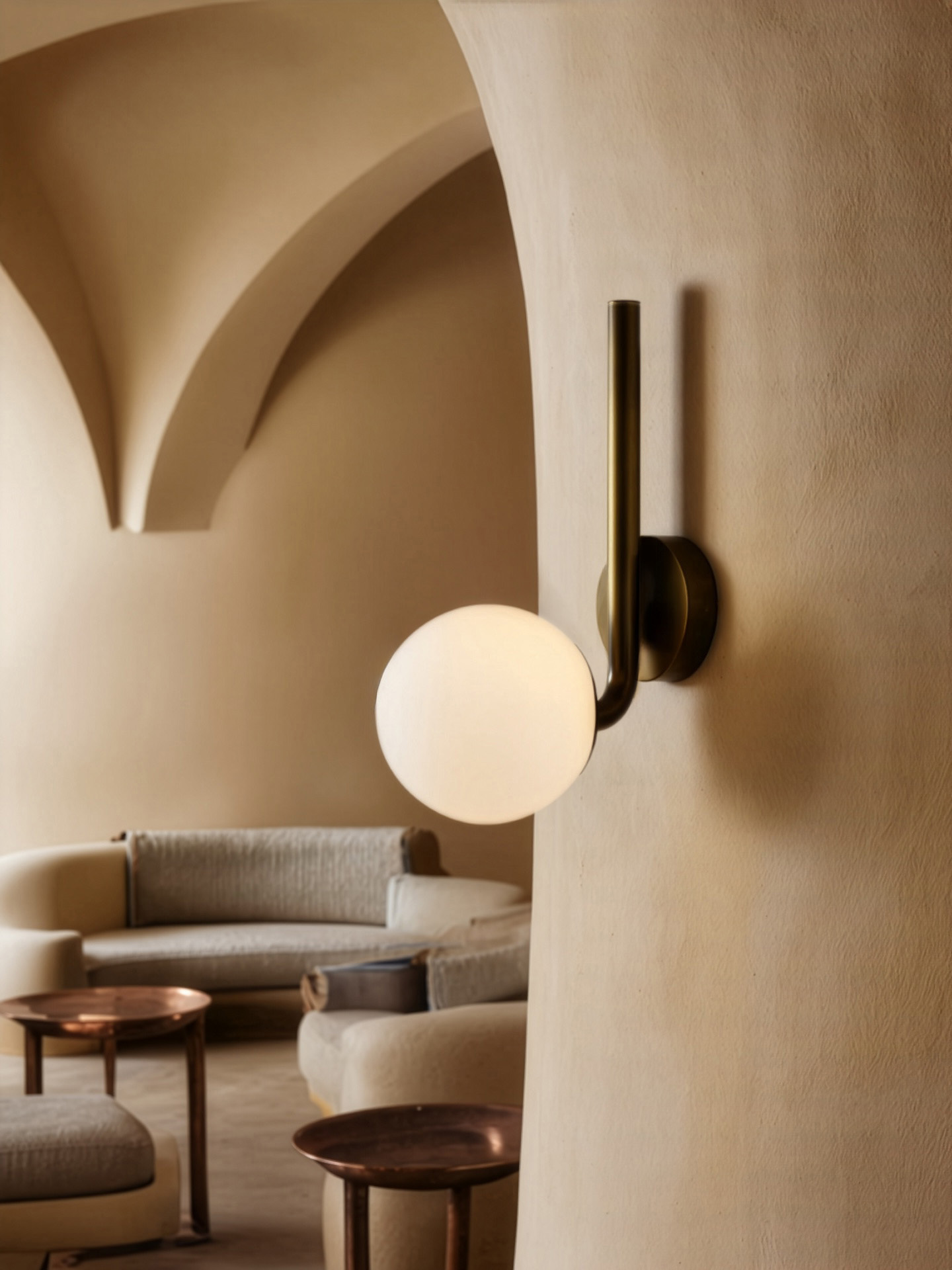 Tubular MD brass and glass wall sconce by Schwung, featuring a curved brass arm and glowing glass sphere, handcrafted for refined interior lighting.