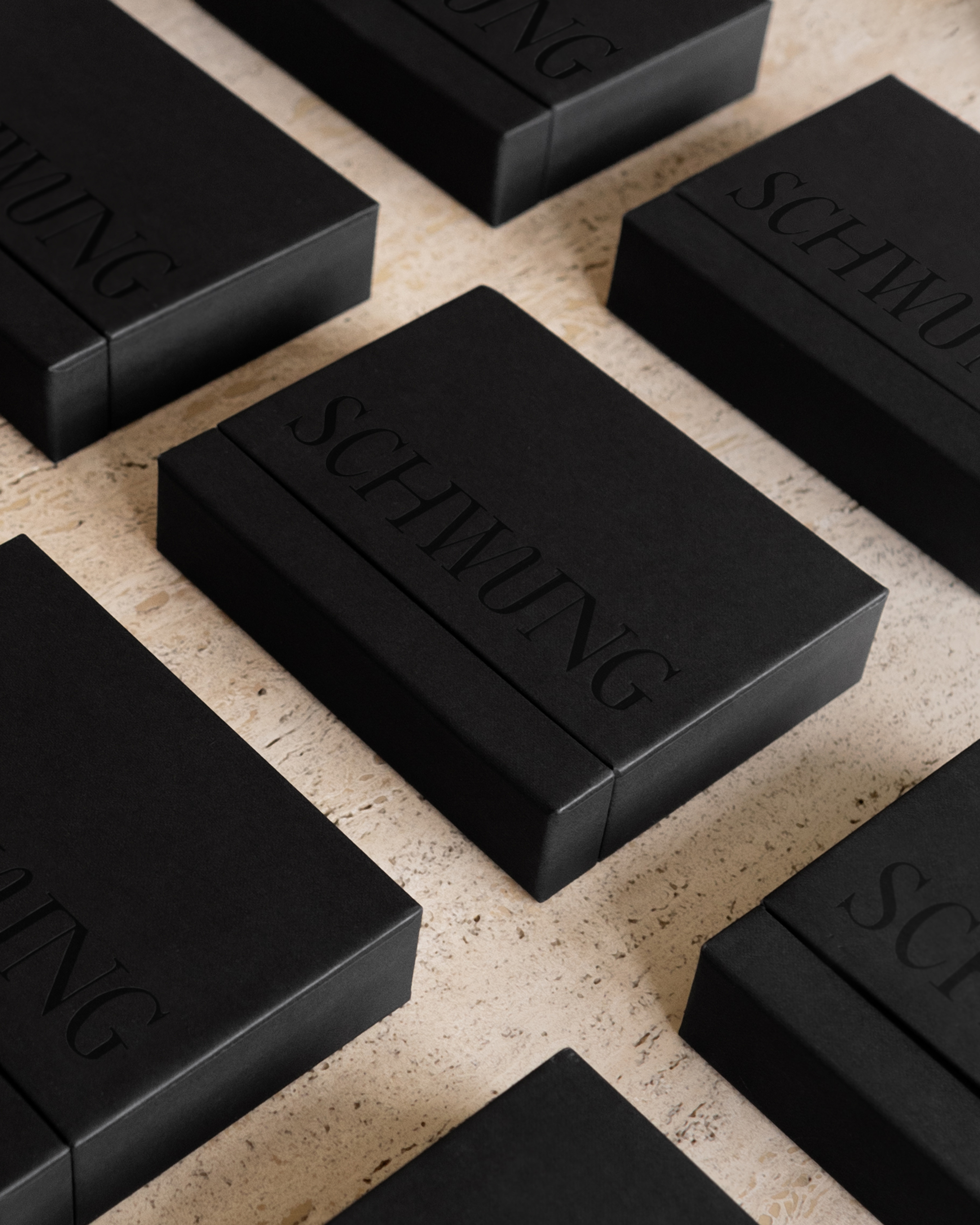 Schwung Small Finish Sample Box with 10 brass finish sample cards on travertine surface.