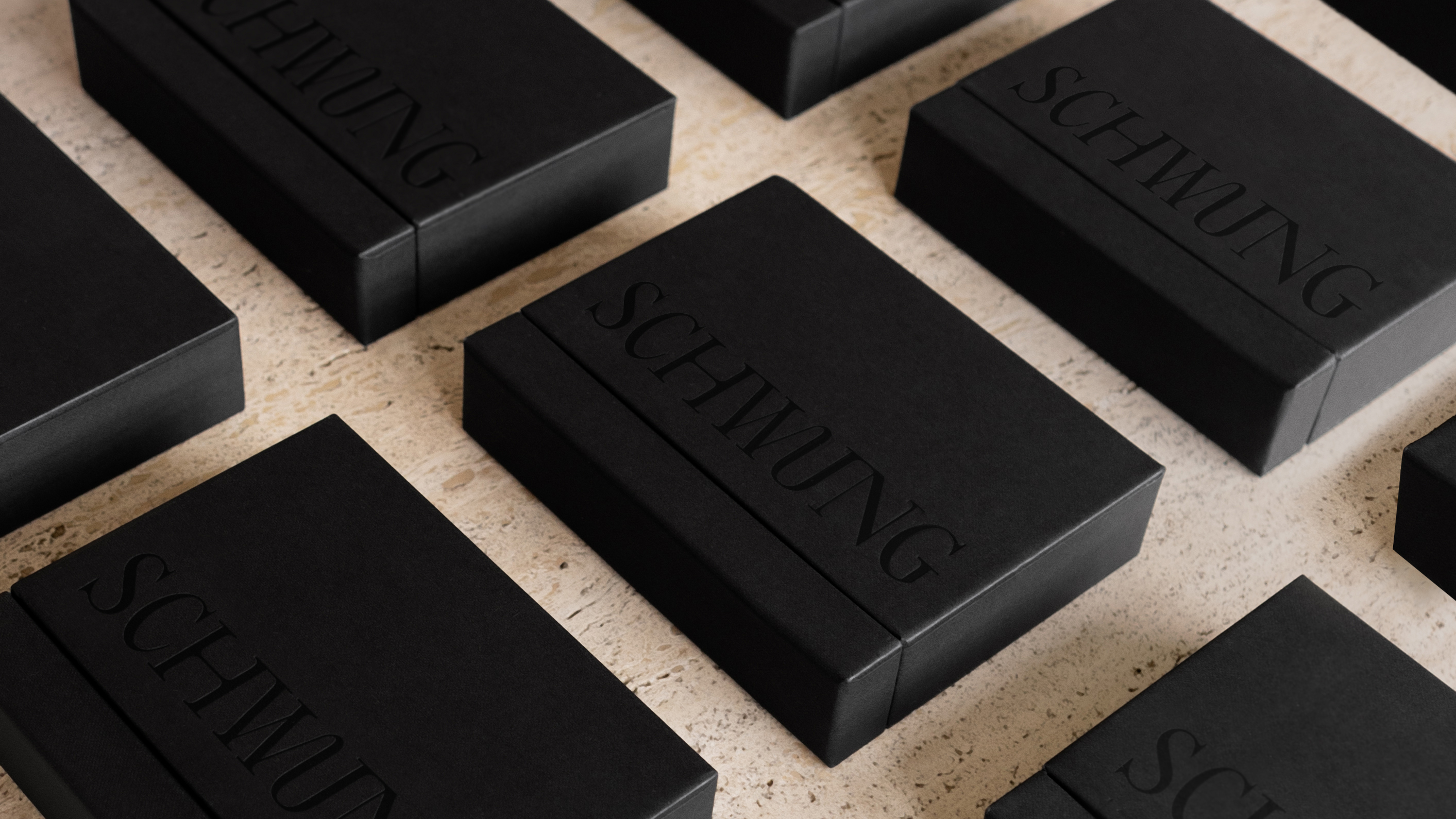 Schwung Small Finish Sample Box with 10 brass finish sample cards on travertine surface.
