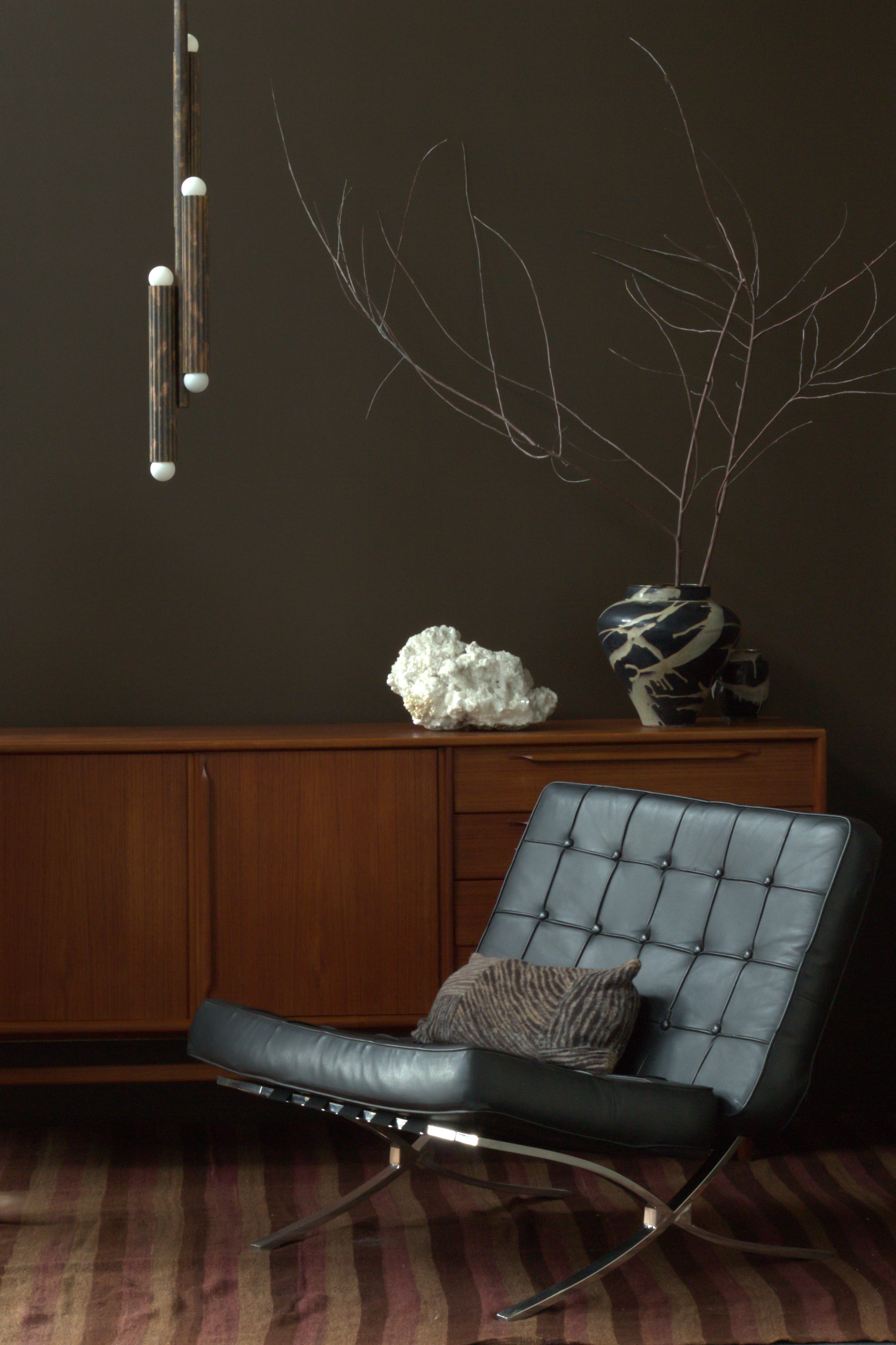 Vesta pendant in rose ash finish, suspended above a refined interior with wooden sideboard and leather lounge chair by Schwung