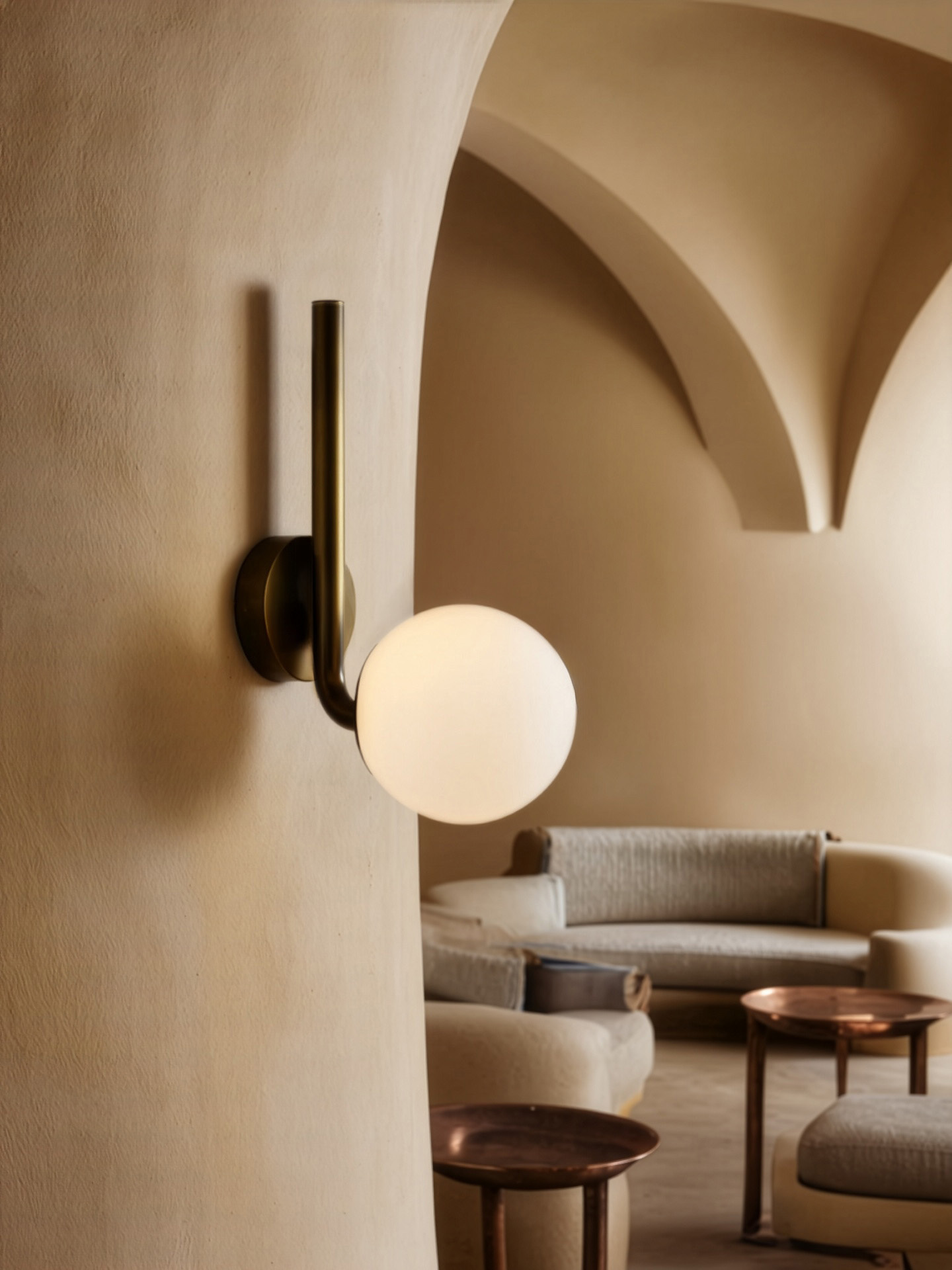 Tubular MD brass and glass wall sconce by Schwung, featuring a curved brass arm and glowing glass sphere, handcrafted for refined interior lighting.
