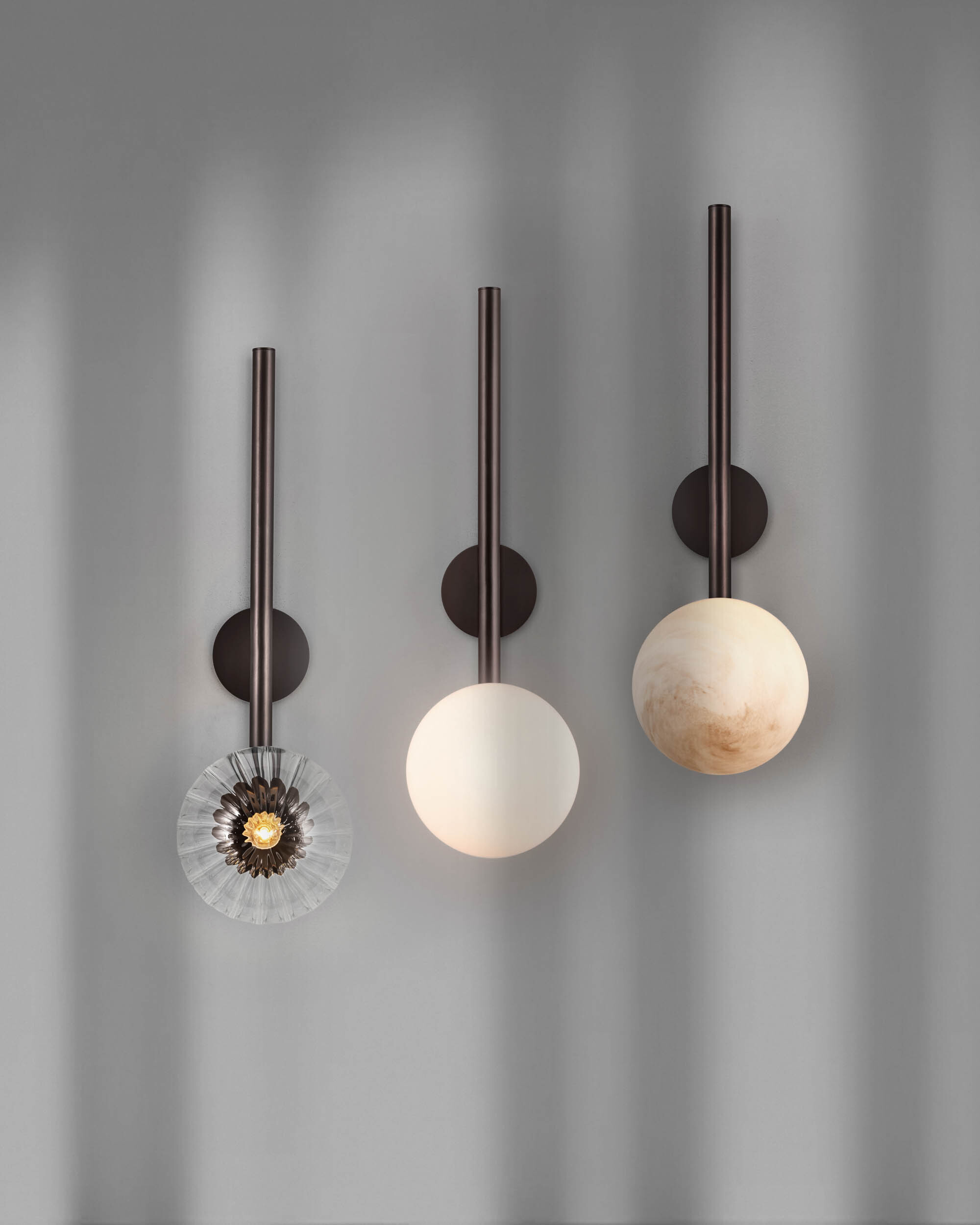 Three Tubular LG brass and glass wall sconces in a Classic Bronze finish, handcrafted by Schwung, showcasing Opal Matte, Dries wavy glass and Marble glass shade options available in the collection.