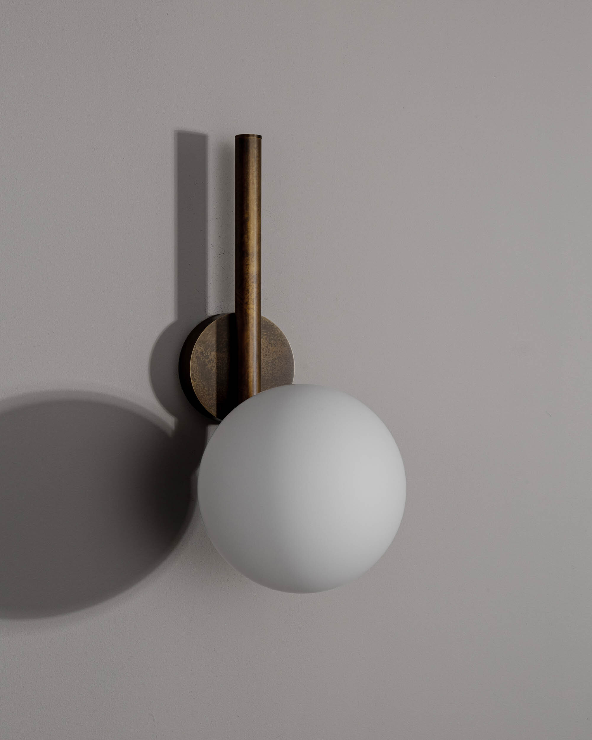 Tubular MD brass and glass wall sconce in a Classic Bronze finish with an Opal Matte glass shade, handcrafted by Schwung.
